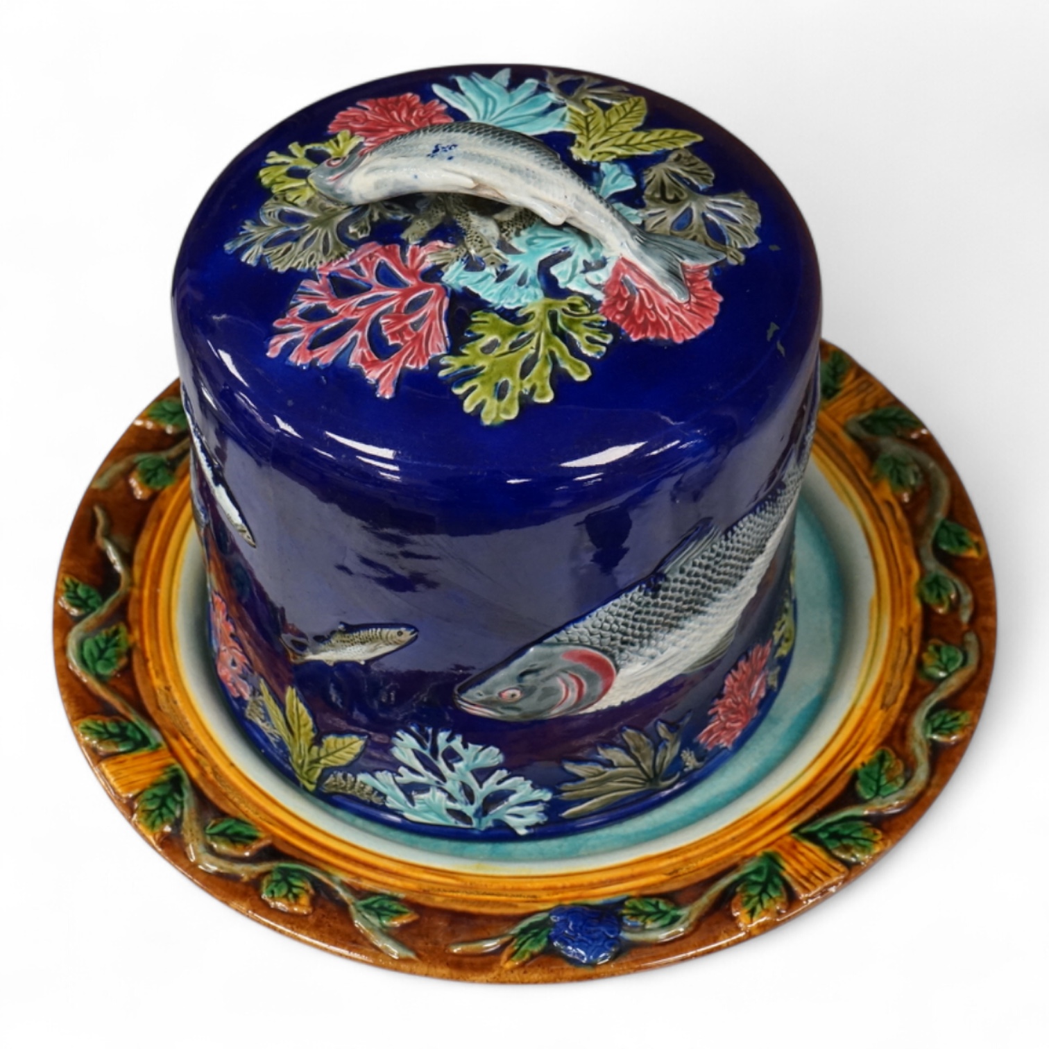 A Victorian majolica cheese dome decorated with fish and seaweed, and a later dish, dome 23cm high, 23cm diameter, dish 24cm internal diameter
